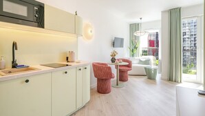 Une cuisine moderne équipée d’un four à micro-ondes encastré, d’un évier et d’un coin repas avec des chaises et une table rouges.