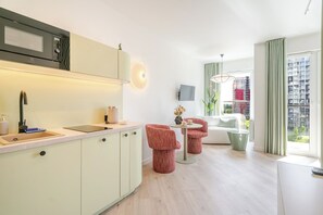 Una cocina moderna con microondas integrado, un lavamanos y una zona de comedor con sillas rojas y una mesa.