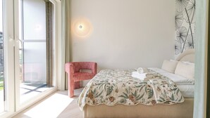 Une chambre à coucher avec un lit, une chaise, une lampe fixée au mur et une fenêtre.