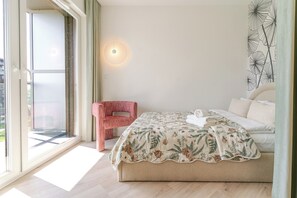 Ein Schlafzimmer mit einem Bett, einem Sessel, einer Wandlampe und einem Fenster.