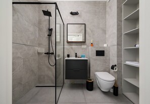 Een moderne badkamer met douche, toilet en wastafel.