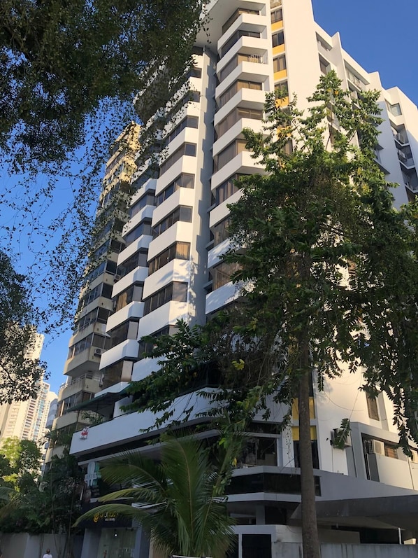 Un immeuble à plusieurs étages, doté de balcons et entouré d’arbres.