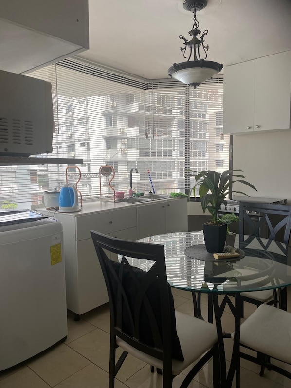 Eine moderne Küche mit Backofen, einem Esstisch mit Stühlen und Blick auf eine Skyline durch große Fenster.