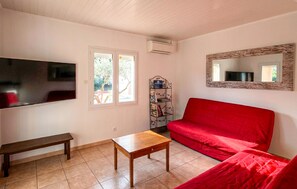 A living room with a red sofa, a wooden coffee table, a bench, a TV, and a bookshelf. - Stunning home in Sampzon (Sampzon)