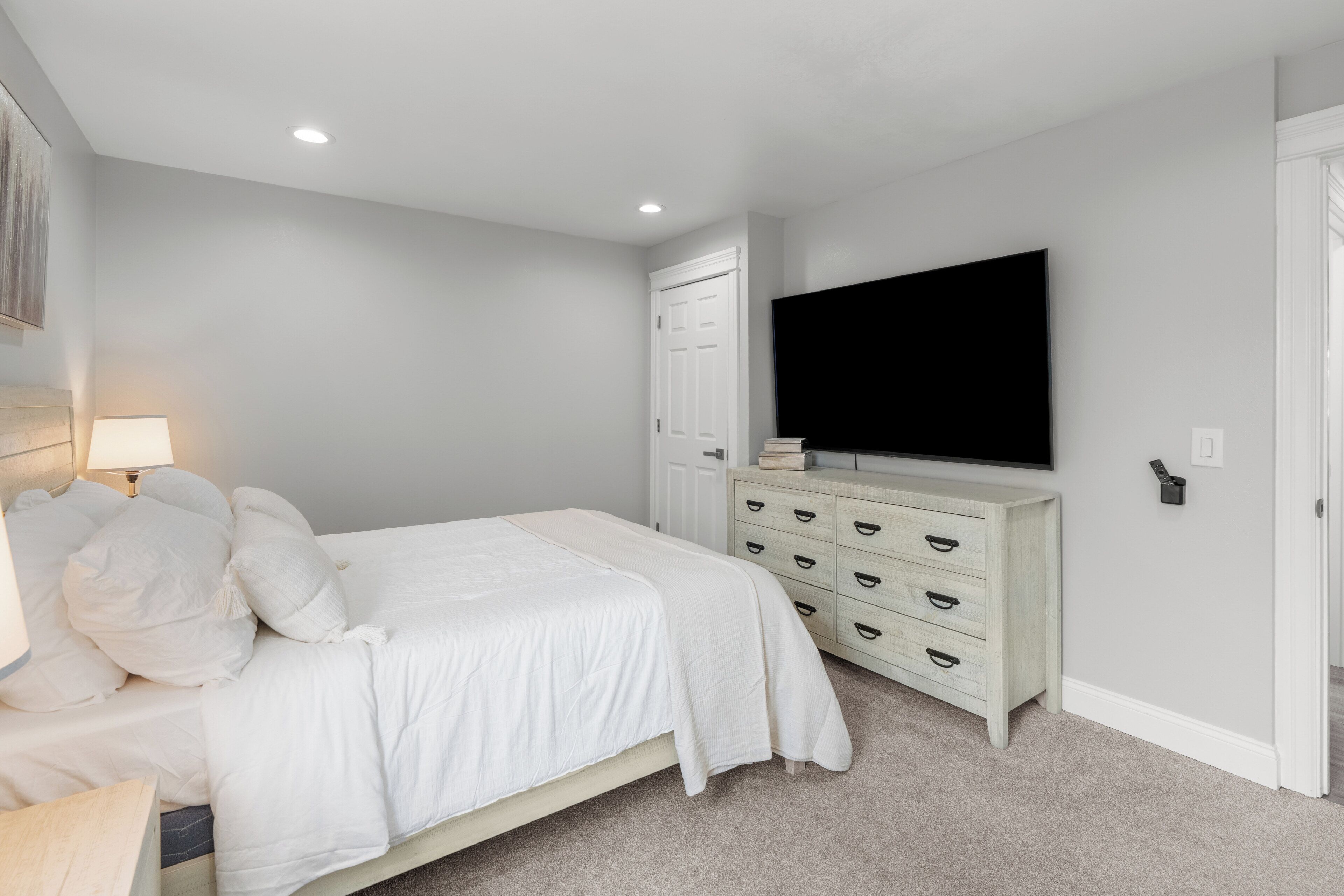 Ein Schlafzimmer mit Bett, Schminktisch, Fernseher und Tür.