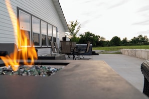 Un patio con una chimenea, mobiliario exterior y vistas a una casa.