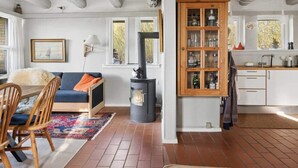 Una sala de estar acogedora con un sofá, una mesa de comedor con sillas, una chimenea y una zona de cocina con armarios y encimera.