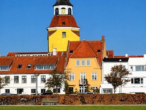 A building with a clock tower, a yellow facade, and a red roof.
