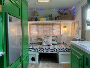 Una habitación compacta con una cama, un pequeño espacio kitchenette y un armario verde.