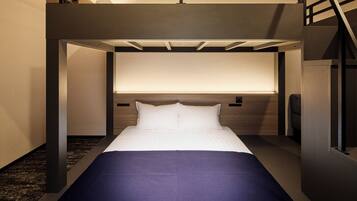 Habitación de hotel moderna con cama, cabecera con panel de luz y alfombra oscura.