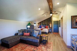 Ein schickes Schlafzimmer im Loft-Stil mit einem großen Bett, einer Couch und einem Deckenventilator.