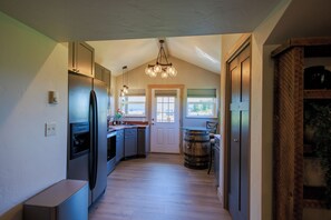 A kitchen with a refrigerator, sink, and wooden barrel.