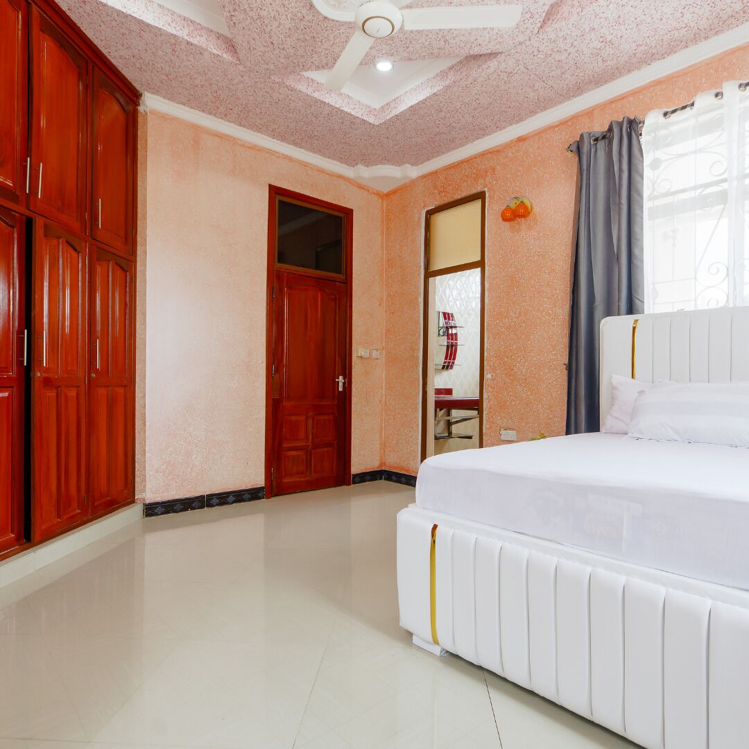 A bedroom with a bed, a wardrobe, a door, and a ceiling fan.