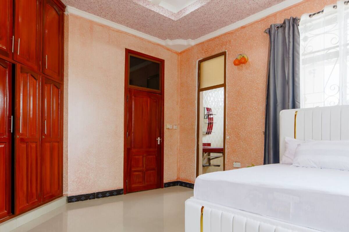 A bedroom with a bed, a wardrobe, a door, and a ceiling fan.