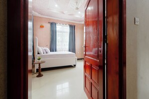 A bedroom with a bed, a small table with a plant, and a wardrobe.
