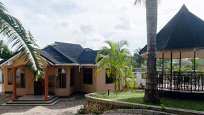 A building with a curved roof, a covered outdoor seating area, and a stone pathway.