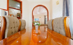 A conference room with a polished wooden table, two upholstered chairs with wooden armrests, and a vase with flowers on the table. - Cozy Tanzania  (Dar es Salaam)