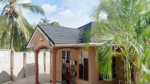 A small building with a tiled roof, a porch with a column, and a gate.