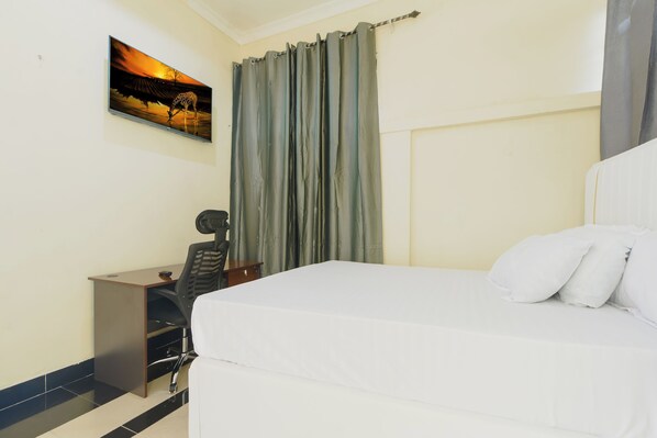 A bedroom with a bed, a desk, a chair, a curtain, and a painting on the wall.