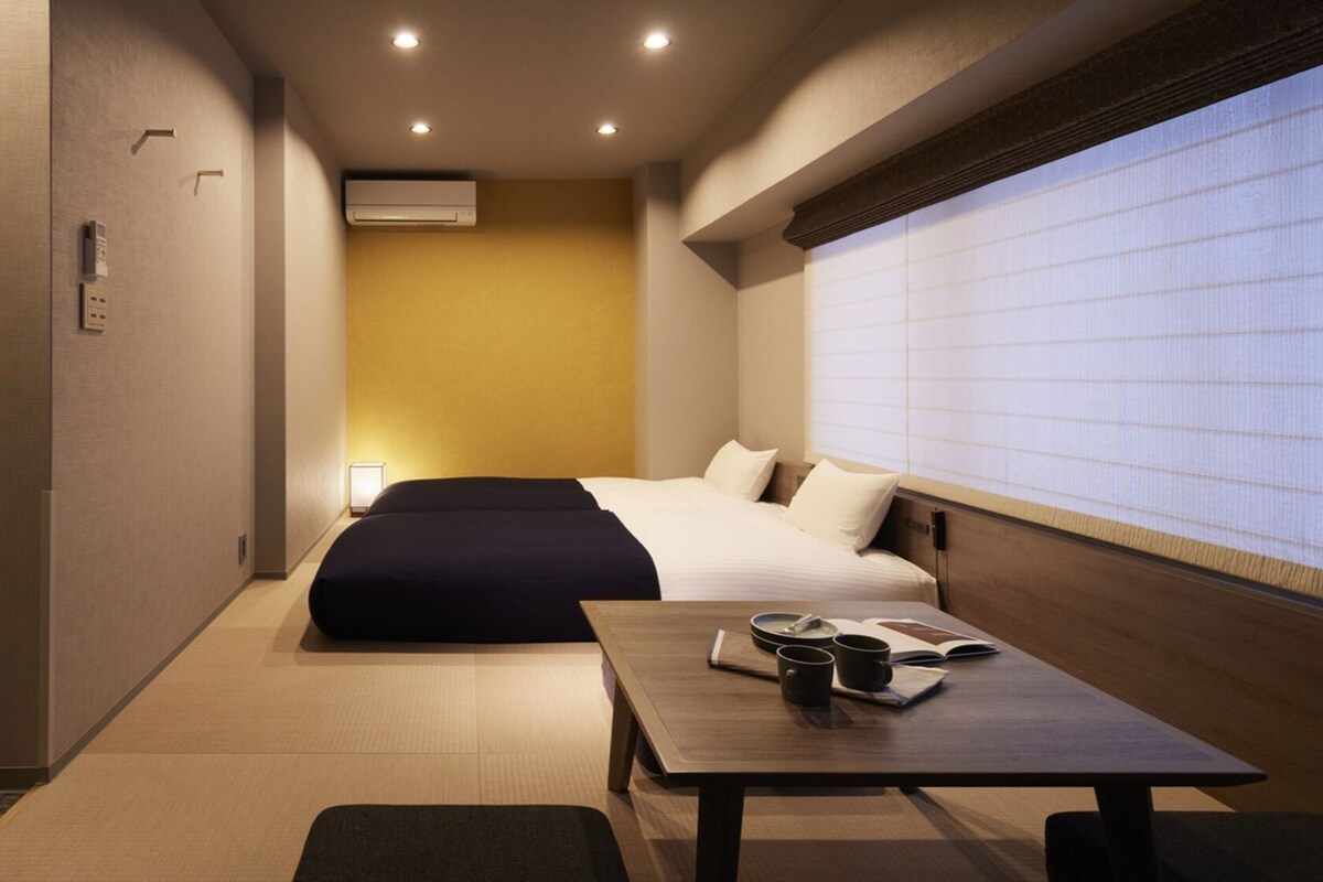 Ein Hotelzimmer mit einem Bett, einem Tisch mit Buch und Tasse sowie einem Fenster mit Blick.
