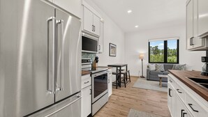 Una cucina moderna con elettrodomestici in acciaio inossidabile, una zona pranzo con tavolo e sedie, e vista su spazi verdi.