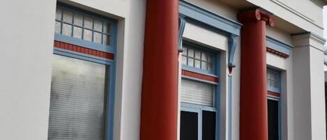 A building with three columns, a door, and windows with blinds.