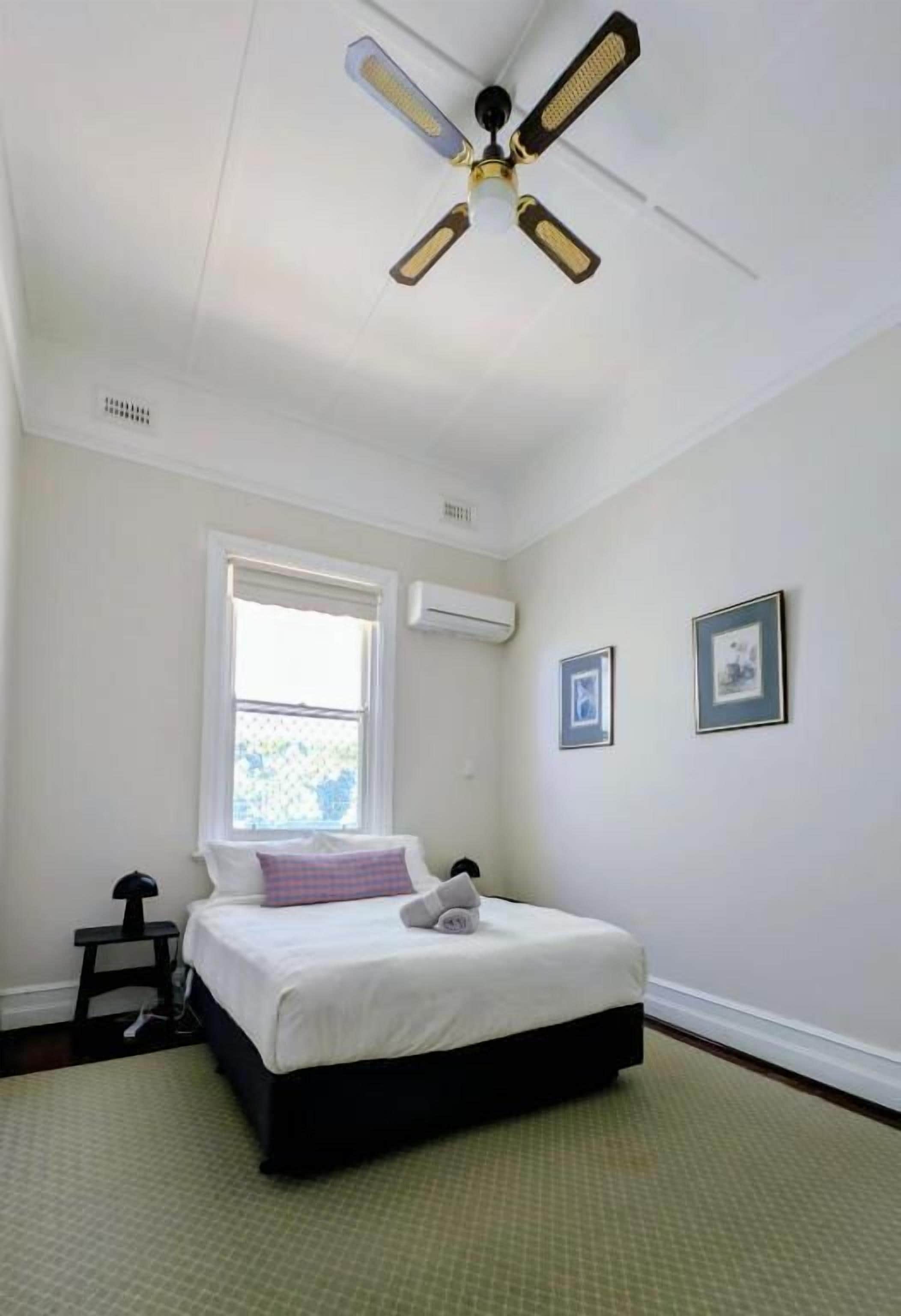 Una camera da letto con un letto, una ventola a soffitto, una finestra e un condizionatore.