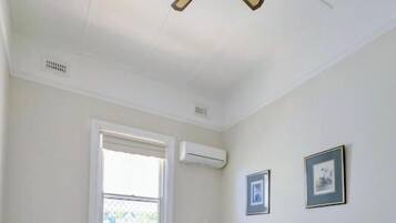 Una camera da letto con un letto, una ventola a soffitto, una finestra e un condizionatore.