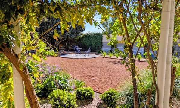 A garden with a circular seating area, a pergola, and various plants.