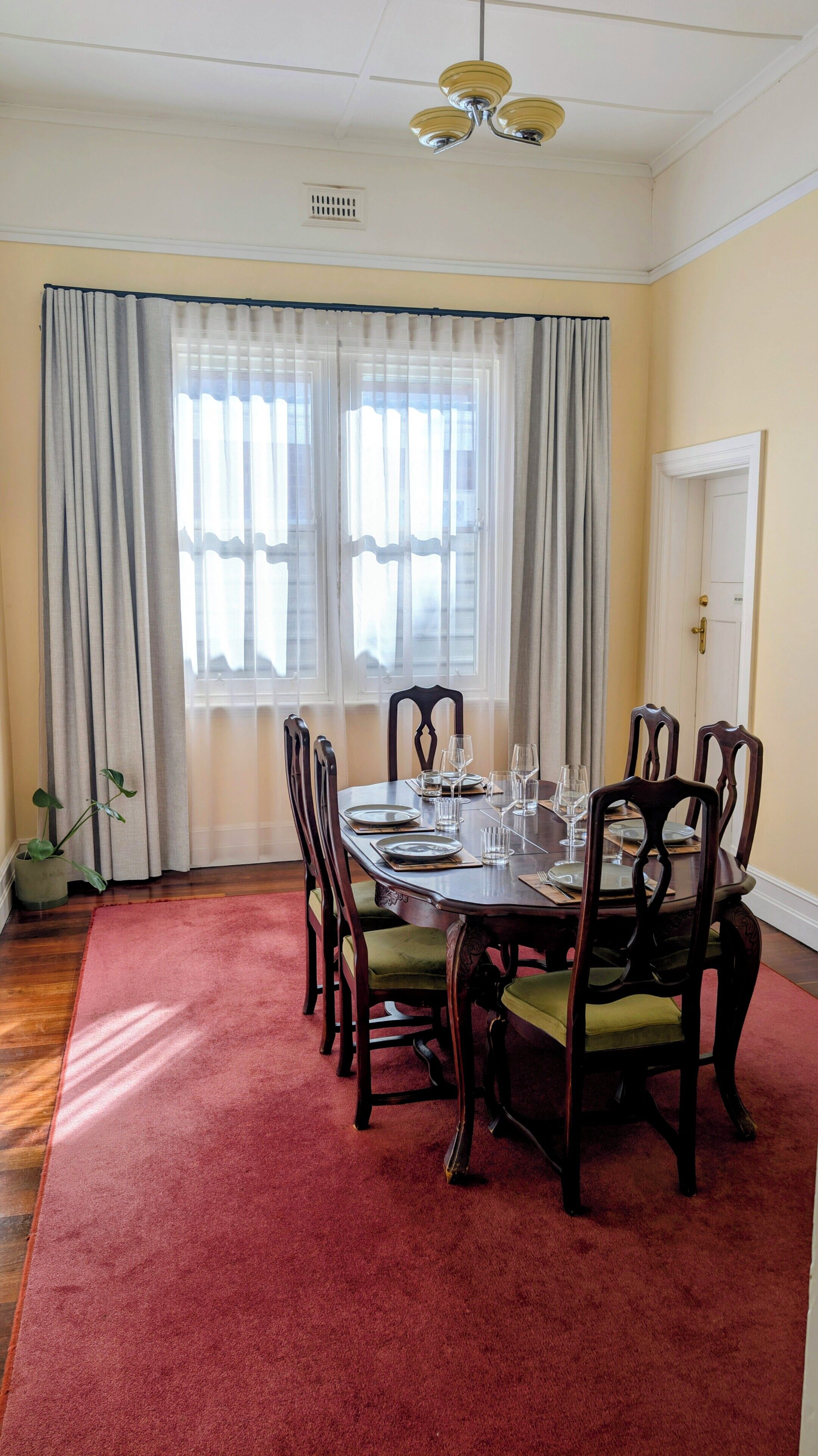 A dining room with a round table, six chairs, and a red carpet.