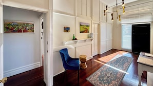 A hallway with a blue chair, a patterned rug, and a painting on the wall. - The Merredin Treasury (Merredin)