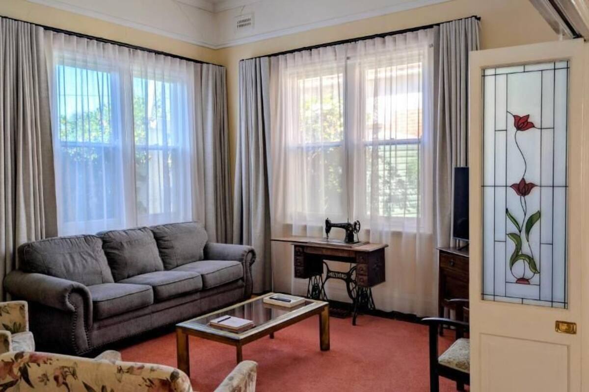 A living room with a sofa, a coffee table, a sewing machine, and a door with a stained glass window.