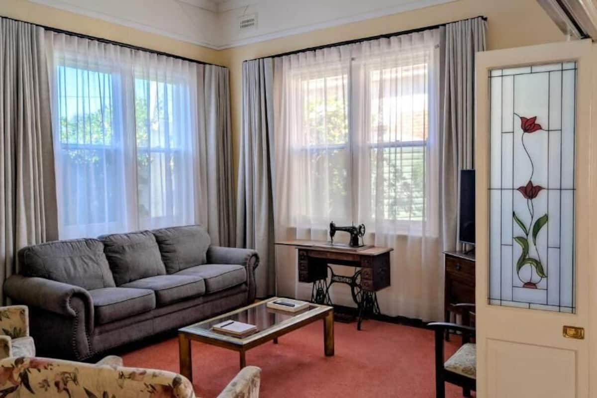 Una sala de estar con un sofá, una mesa de centro, una máquina de coser y una puerta con un vitral.