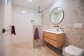 A modern bathroom with a glass shower enclosure, a wooden vanity, and a large mirror.