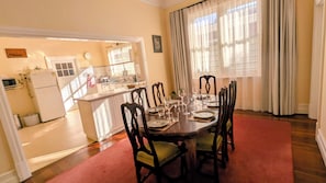 Un comedor con una mesa preparada para cuatro, cocina al fondo y una alfombra roja que lleva a la puerta.