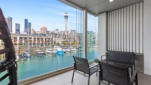 Ein Balkon mit Blick auf einen Yachthafen und eine Stadtlandschaft, darunter ein markanter Turm.