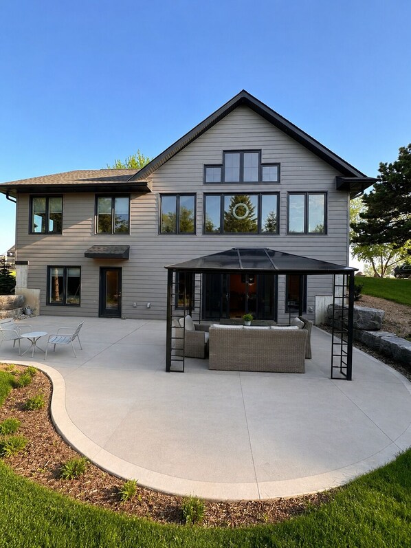 A modern two-story house with a covered patio area featuring outdoor furniture and a pergola. - Vineyard Escape Near Bayfield (Bayfield)