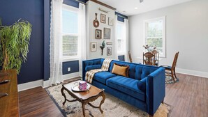 Ein Wohnzimmer mit blauem Sofa, einem Holztisch und einem Deckenventilator.