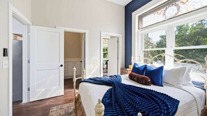 Ein Schlafzimmer mit Bett, Fenster mit Blick, Tür und Nachttisch.