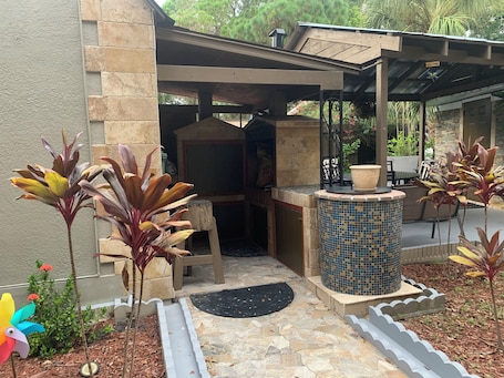 A covered outdoor area with a stone wall, a tiled column, and potted plants.. Eirini’s Home