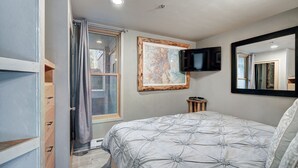 A bedroom with a bed, a television, a map on the wall, and a window with curtains. - Beautiful Keystone Condo: Perfect Leaf Peeping! (Keystone)