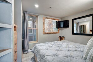 A bedroom with a bed, a television, a map on the wall, and a window with curtains. - Beautiful Keystone Condo: Perfect Leaf Peeping! (Keystone)