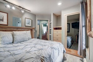 A bedroom with a bed, dresser, and a television in the adjacent room. - Perfect Keystone Ski Home: 2 Min Walk to Gondola! (Keystone)
