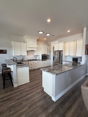 A modern kitchen with white cabinets, a large island, and built-in appliances. - Fantastic 5-br, 3.5ba house with pool, hot tub AC located in Graham county, AZ. (Pima)