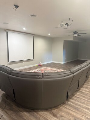 A room with a large screen, ceiling fan, and a built-in seating area. - Fantastic 5-br, 3.5ba house with pool, hot tub AC located in Graham county, AZ. (Pima)