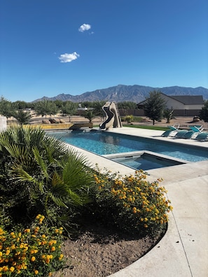 A pool with a water slide, surrounded by greenery and a mountain view. - Fantastic 5-br, 3.5ba house with pool, hot tub  AC located in Graham county, AZ. (Pima)