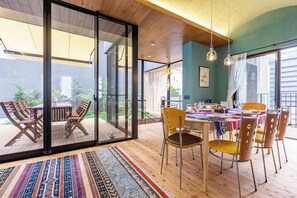 Een eetgedeelte met een tafel voor vier personen, omringd door stoelen en een uitzicht op het omliggende landschap door glazen deuren.
