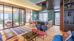 Espaço moderno para viver, com cozinha, área de refeições e sala de estar com vista para o exterior.
