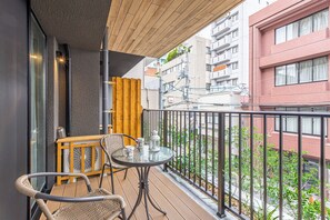 Ein Balkon mit Tisch und Stühlen, einem Ventilator und Blick auf die Stadt.