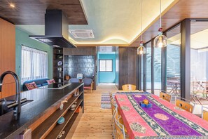 Eine moderne Küche mit einer zentralen Kochinsel, Holzboden und einem Essbereich mit bunten Tischdecken.